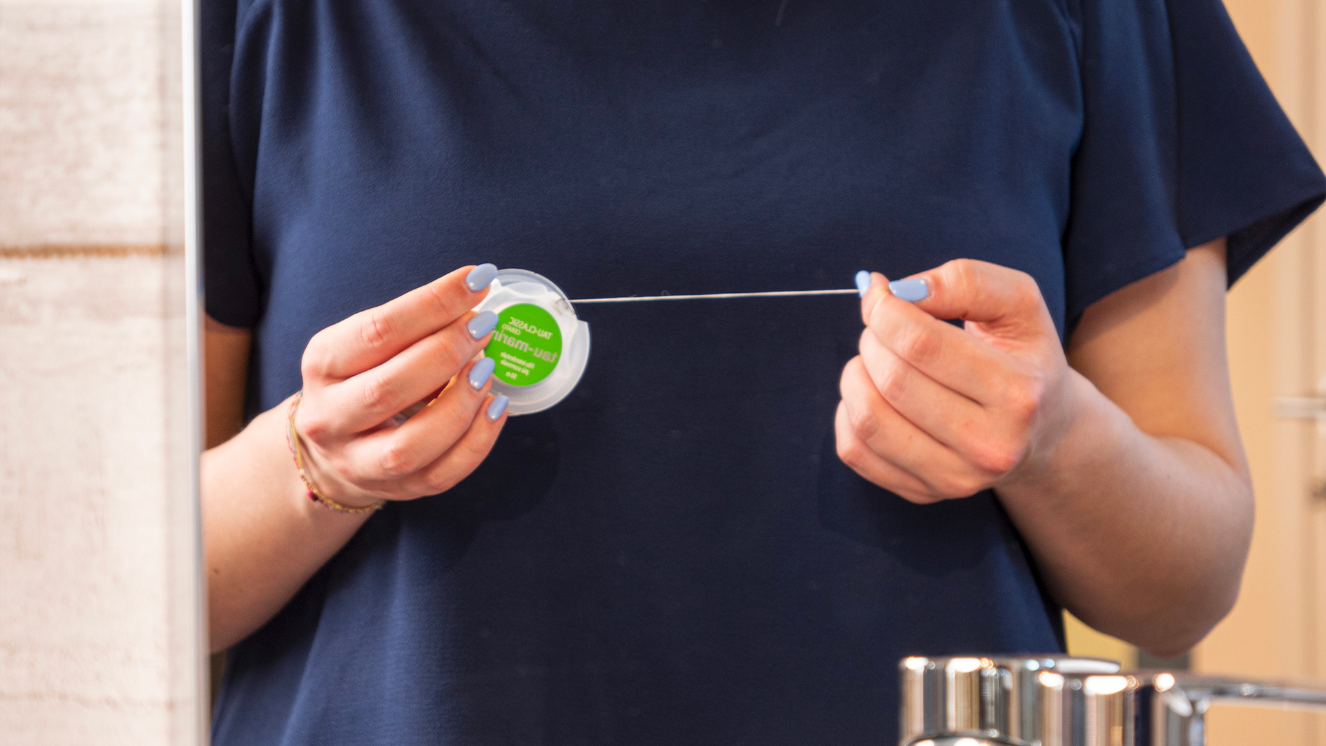 donna utilizza filo interdentale tau-marin per curare la propria igiene orale