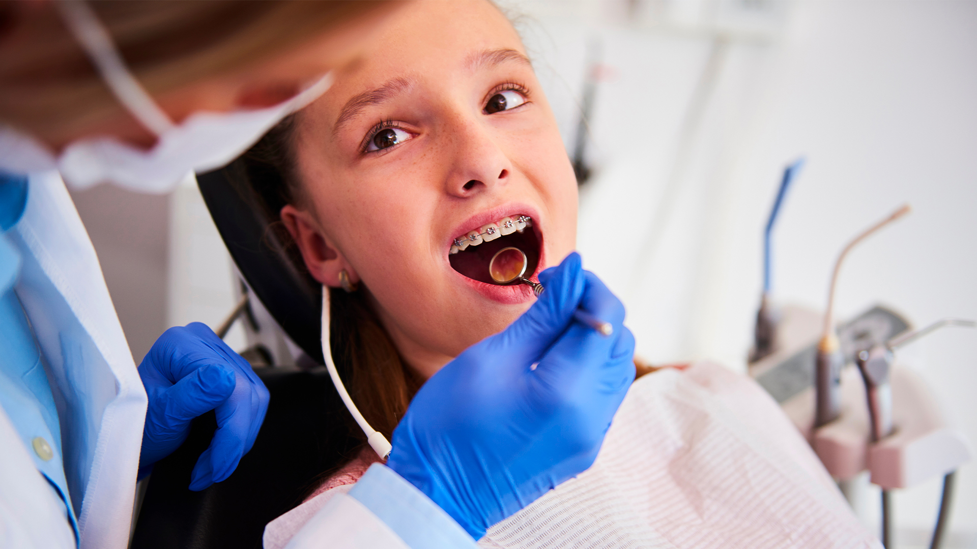 dentista spiega a bambina come lavare i denti con l’apparecchio